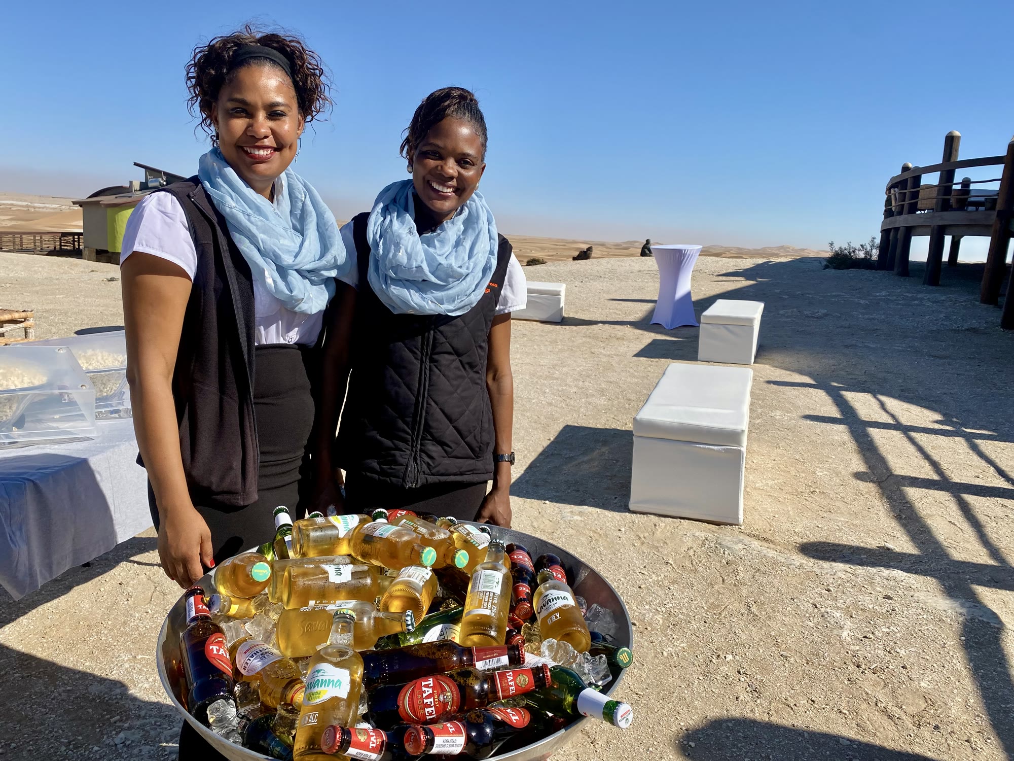 Two members of the Desert Breeze team welcoming guests beside the Namib dunes