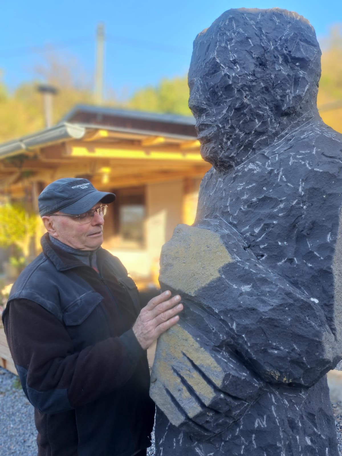 Knut Hüneke beside a hand-carved stone figure